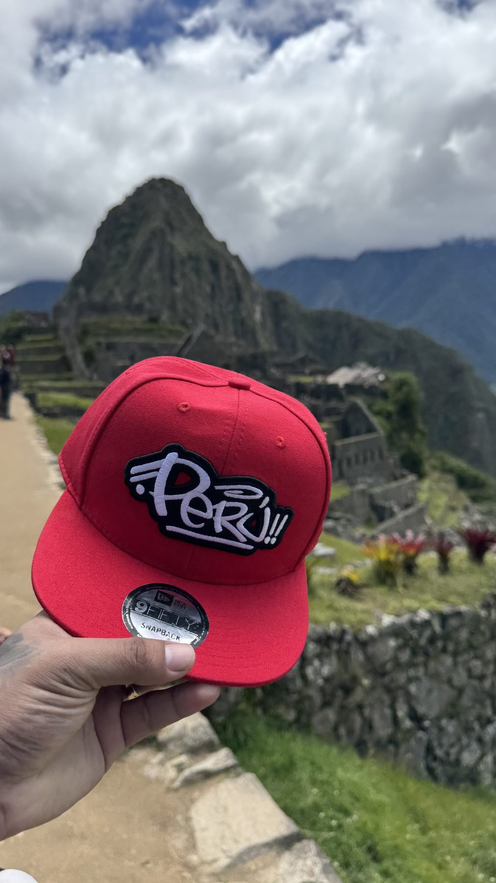 Red Perú snapback held up at Machu Picchu