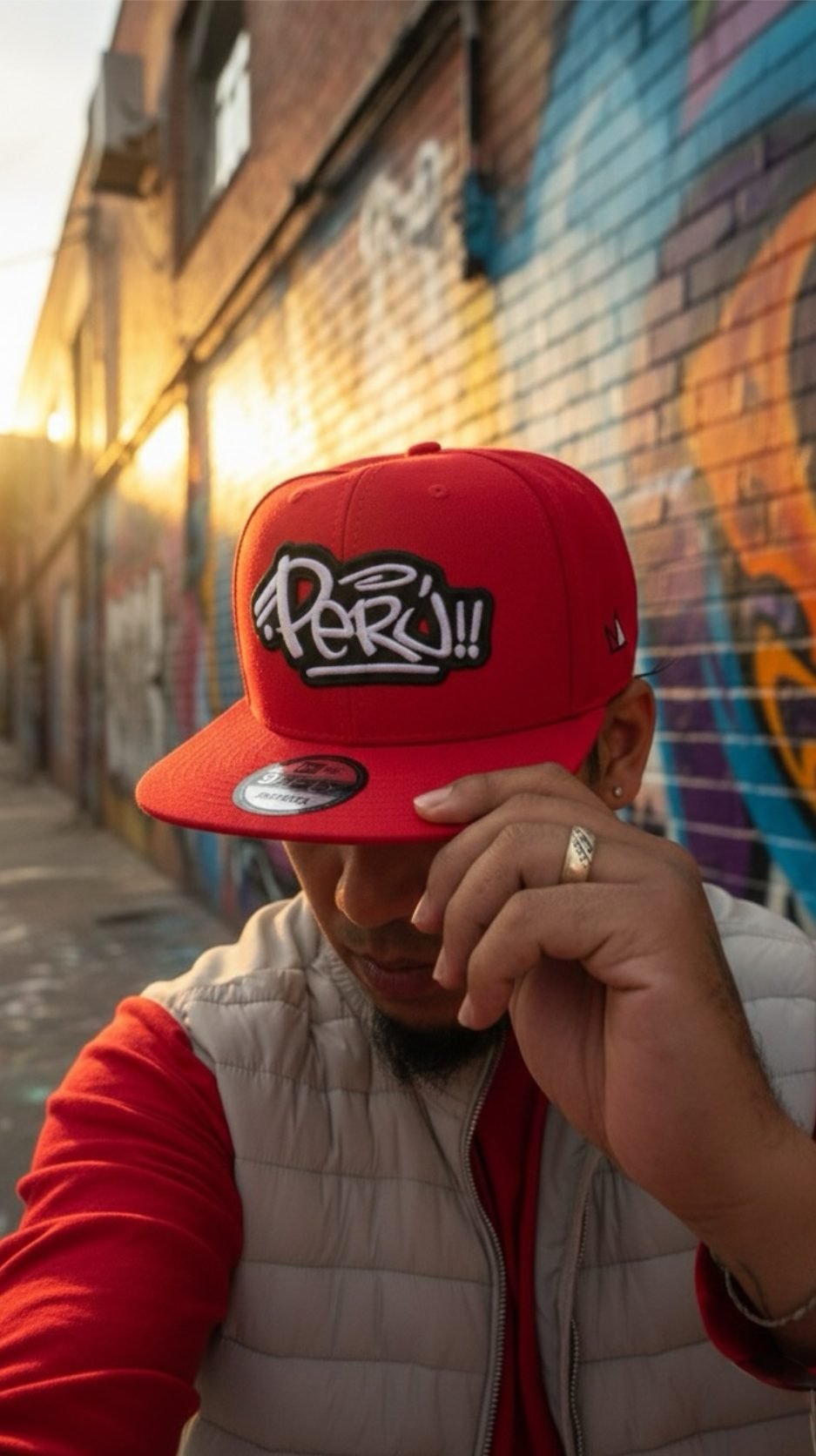 Red Perú snapback pulled down low in a graffiti alley at sunset